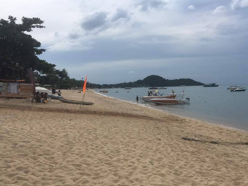 หาดทรายบ่อผุดกับเรือที่จอดลอยลำและเกาะในอ่าว