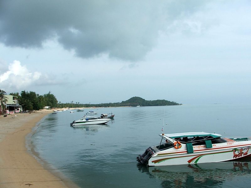 ชายหาดโค้งของบ่อผุดและเรือเร็วจอดลอยลำบนน้ำทะเลสีเขียว